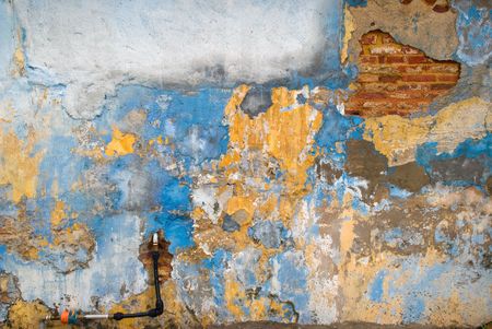 A dilapidated grungy wall with a patch of bricks showingの写真素材