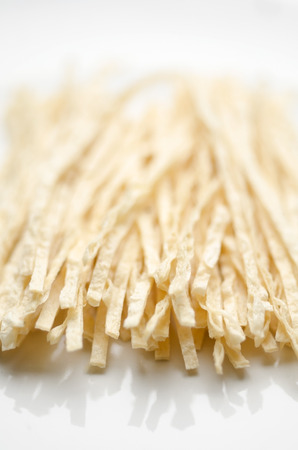 A vertical image of strips of japanese fish snacks on a white ceramic plateの写真素材