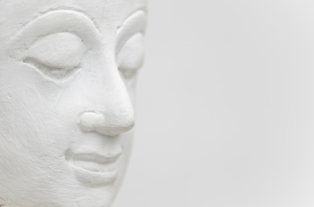 A horizontal photographic image of the face of a white Buddha against a white background.の写真素材