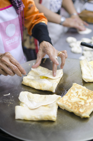 Women making roti pastries at a street food stand in Chiang Mai, Thailand.の写真素材