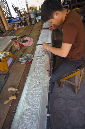 Chiang Mai, Thailand - January 27, 2015: An artisan sculpts a sheet of silver at Wat Srisuphan, dubbed the Silver Temple, in Chiang Mai, Thailand on January 27, 2015.のeditorial素材