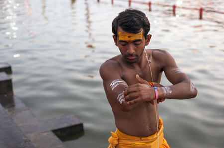 Ujjain, Madhya Pradesh, India - May 18, 2016: A young priest paints his arm before a fire ceremony called Ã¢ï¿½ï¿½aartiÃ¢ï¿½ï¿½ at the Kshipra River during the Kumbh Mela religious festival in Ujjain, India on May 18, 2016. Kumbh Mela is the largest gatheのeditorial素材