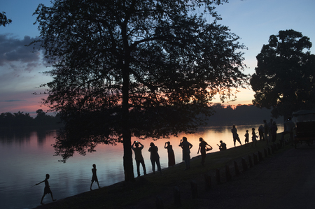An horizontal image of people photographing a sunset over a lake with their mobile phones.の写真素材