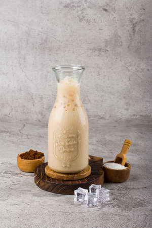 iced coffee latte with glass bottle on wooden coaster and white background textureの写真素材