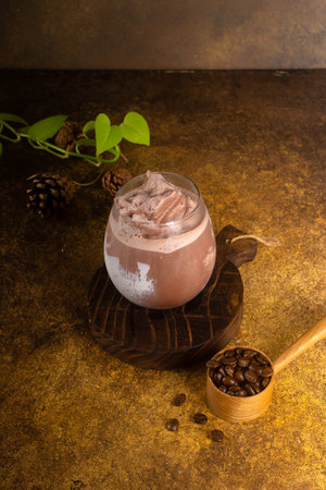 chocolate drink with ice in glass and hot in mug, on rustic wooden tray and authentic backgroundの写真素材