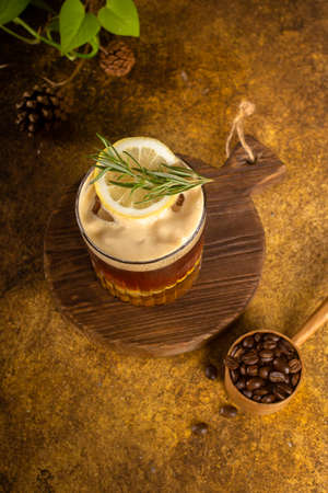 iced coffee with lemon sparkling water on rustic coaster and with rosemary on topの写真素材