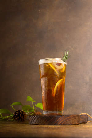freshly lemon tea made with ice in glass with slice of lemon and rosemary, on rustic wooden tray and authentic backgroundの写真素材
