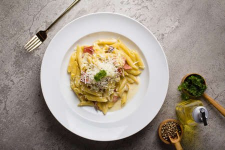 Italian Pasta penne cream sauce with minced beef sauce and parmesan cheese in white plate on texture tableの写真素材