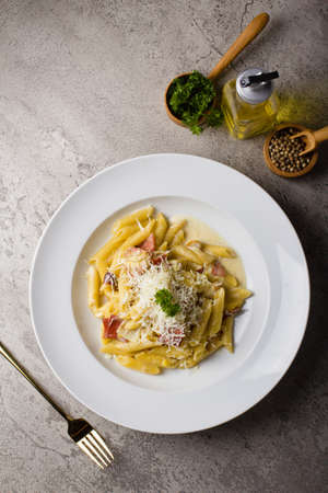 Italian Pasta penne cream sauce with minced beef sauce and parmesan cheese in white plate on texture tableの写真素材