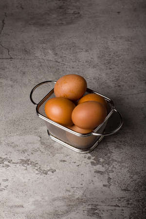 chicken egg on metal basket and grey texture backgroundの写真素材