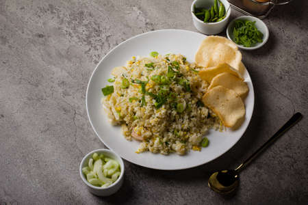 fried rice or nasi goreng kampung, with scrambled egg, spring onion and cracker on white plateの写真素材
