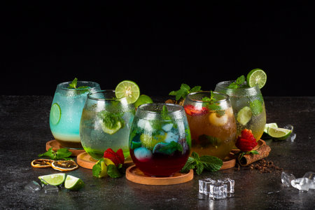 Several cocktail in glass with ice cube, strawberry, lime, ginger and mint leaf on texture tableの写真素材