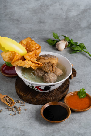 Bakso or indonesian meatball served with broth soup, tofu, noodle and deep fried wonton or dumpling on white bowlの写真素材