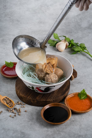 Bakso or indonesian meatball served with broth soup, tofu, noodle and deep fried wonton or dumpling on white bowlの写真素材