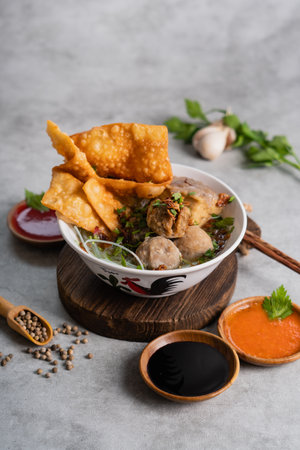 Bakso or indonesian meatball served with broth soup, tofu, noodle and deep fried wonton or dumpling on white bowlの写真素材
