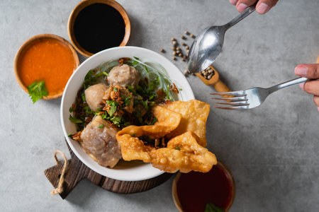 Bakso or indonesian meatball served with broth soup, tofu, noodle and deep fried wonton or dumpling on white bowlの写真素材