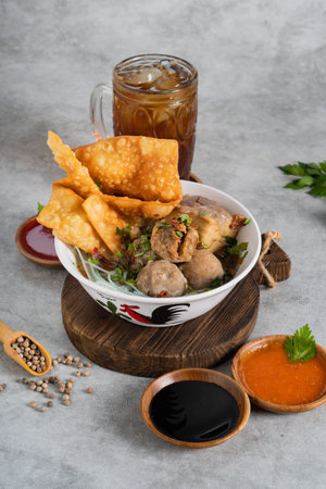 Bakso or indonesian meatball served with broth soup, tofu, noodle and deep fried wonton or dumpling on white bowlの写真素材