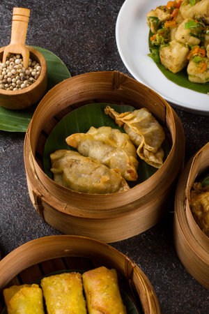 Chinese dumplings in bamboo steamer on black stone background.の写真素材