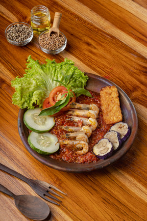 Deep fried shrimps or prawn with spicy chili sauce or sambal and eggplant in pottery plate on wooden tableの写真素材