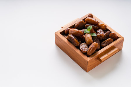 Dried dates fruit in wooden tray isolated on white background.の写真素材