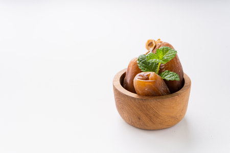 Dried dates fruit in wooden mini bowl isolated on white background.の写真素材