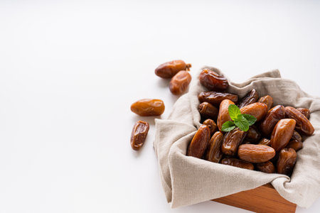Dried dates fruit in wooden tray with soft napkin isolated on white background.