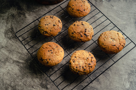 Homemade chocolate chip cookies on black baking cooling tray and abstract background