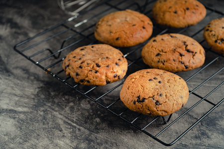 Homemade chocolate chip cookies on black baking cooling tray and abstract background