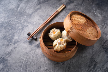 Chinese steamed dumplings or  Dim Sum in bamboo steamer on dark abstract backgroundの写真素材