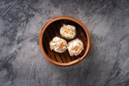 Chinese steamed dumplings or  Dim Sum in bamboo steamer on dark abstract backgroundの写真素材