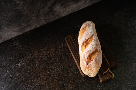 Fresh homemade artisan loaf of baguette breads on rustic background with copy space. sourdough mini...