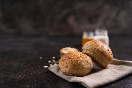 Fresh whole grain brown buns with sesame seeds on rustic background. Healthy artisan bread.の写真素材