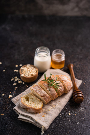 Sliced artisan baguette bread on wooden coaster and rustic background. Sourdough bread.の写真素材