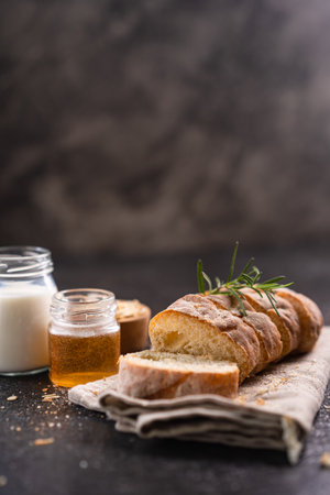 Sliced artisan baguette bread on wooden coaster and rustic background. Sourdough bread.の写真素材