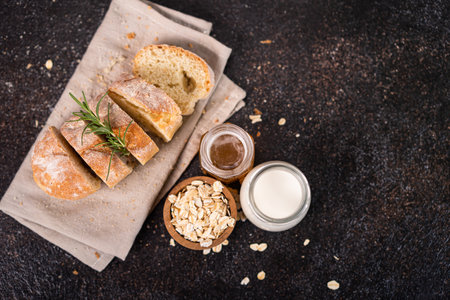 Sliced artisan baguette bread on wooden coaster and rustic background. Sourdough bread.の写真素材