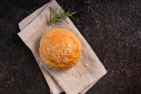 Homemade whole grain brown buns with sesame seeds on rustic background. Healthy artisan bread.の写真素材