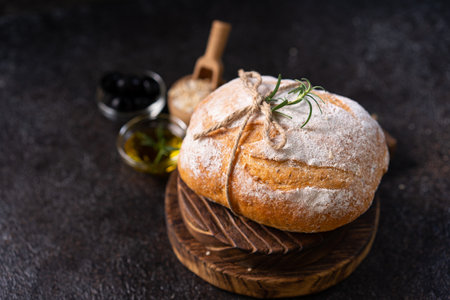 Fresh organic homemade artisan ciabatta bread with herbs, olive oil and olives on dark rustic background. sourdough breadの写真素材