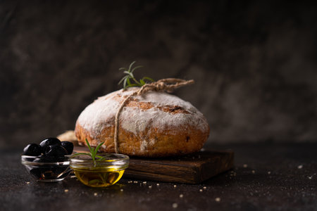 Freshly baked sourdough ciabatta bread with olives and rosemary on a black rustic table. Artisan breadの写真素材
