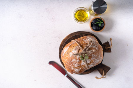 Freshly baked sourdough ciabatta bread with olives and rosemary on a white abstract table. Artisan breadの写真素材