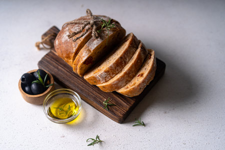 Homemade sourdough ciabatta slice bread with olives and rosemary on a white abstract table. Artisan breadの写真素材
