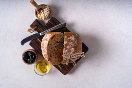 Homemade sourdough ciabatta slice bread with olives and rosemary on a white abstract table. Artisan...