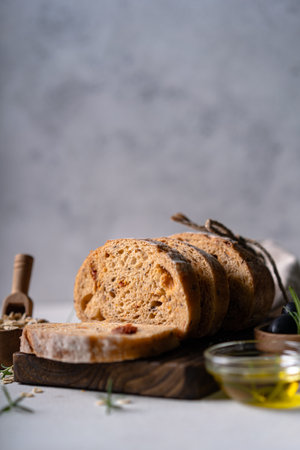 Homemade sourdough ciabatta slice bread with olives and rosemary on a white abstract table. Artisan...