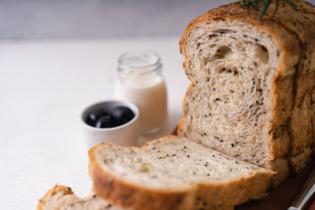 Fresh Sliced Homemade Wholegrain Wheat Bread whit olive oil on white rustic background. Artisan...