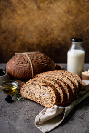 Baked sourdough bread from whole grain flour and pumpkin seeds on a grid, olive oil and black olive...