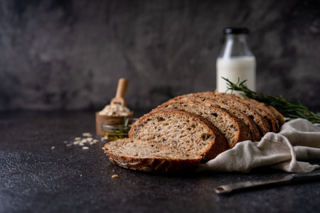 Sliced sourdough bread from whole grain flour and pumpkin seeds on a grid, olive oil and black olive...