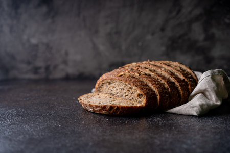 Sliced sourdough bread from whole grain flour and pumpkin seeds on a grid, olive oil and black olive...