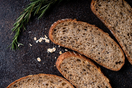 Sliced sourdough bread from whole grain flour and pumpkin seeds on a grid, olive oil and black olive...