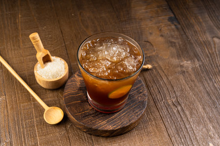 Ice tea in a glass with ice cubes and spoon on wooden background