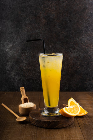 Glass of orange juice with ice cubes and fresh oranges on dark backgroundの写真素材