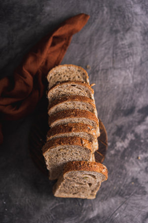 Sliced whole grain loaf bread on dark rustic wooden background